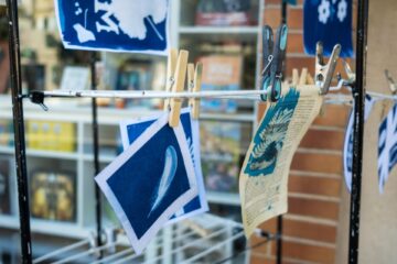 Un cyanotype en train de sécher avec des pinces à linge lors d'un atelier artistique dans une librairie indépendante à Caussade, capturé par le photographe Montauban Cahors spécialisé en ateliers cyanotype